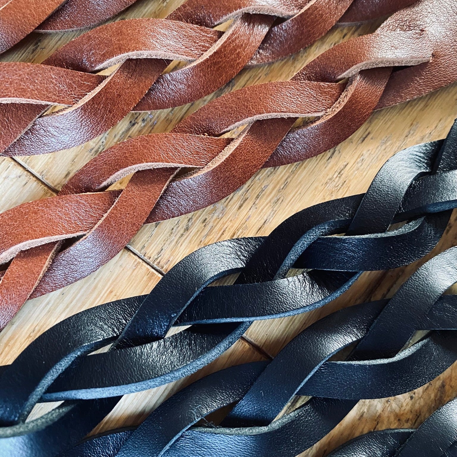 Close-up of braided brown and black leather strips on a wooden surface