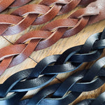 Load image into Gallery viewer, Close-up of braided brown and black leather strips on a wooden surface
