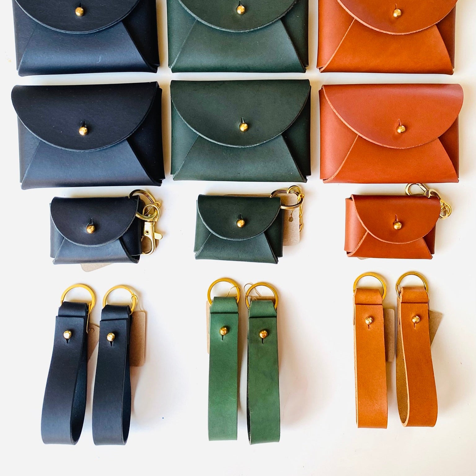 Collection of small leather pouches in various colors with matching straps on a white background.