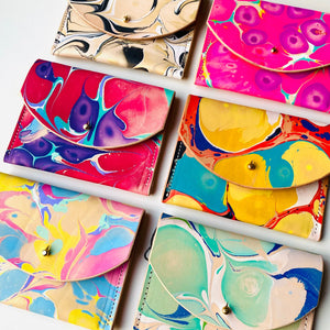 Colorful marbled wallets arranged in a grid on a white background