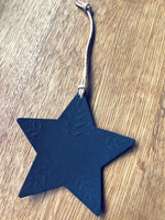 Load image into Gallery viewer, A dark blue star-shaped ornament with embossed leaf patterns, hanging from a silver cord on a wooden surface.

